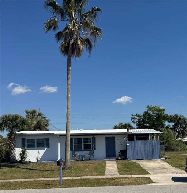 single story home featuring stucco siding, concrete driveway, fence, a carport, and a front lawn