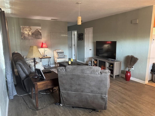 living area with wood finished floors, visible vents, and baseboards