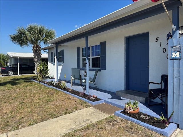 exterior space with covered porch, a lawn, and stucco siding