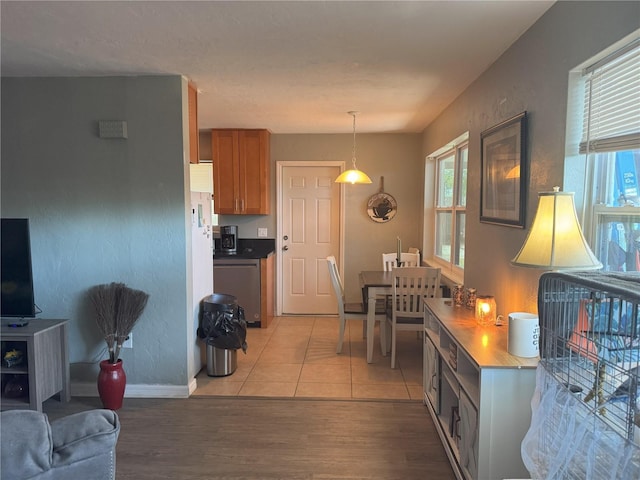 kitchen featuring light wood-type flooring, plenty of natural light, brown cabinets, and dishwasher