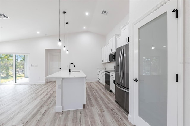 kitchen with visible vents, white cabinets, appliances with stainless steel finishes, a kitchen island with sink, and vaulted ceiling