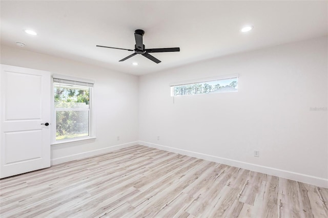 spare room featuring light wood-style floors, a healthy amount of sunlight, and baseboards