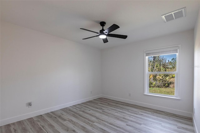 spare room featuring a ceiling fan, visible vents, light wood finished floors, and baseboards