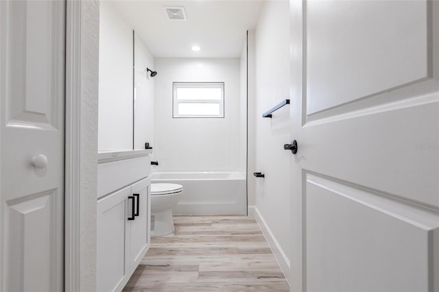 bathroom with toilet, wood finished floors, vanity, visible vents, and  shower combination