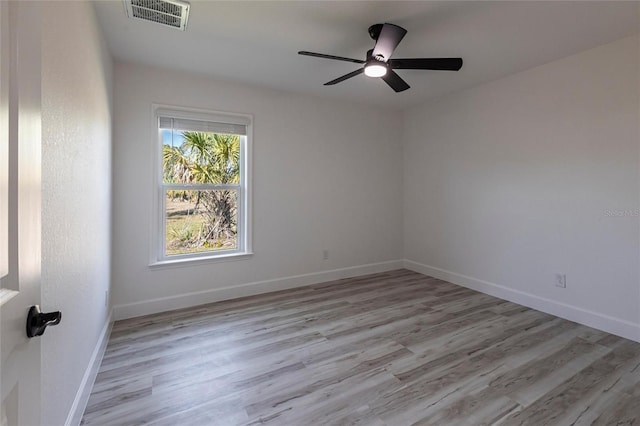 spare room with wood finished floors, visible vents, and baseboards