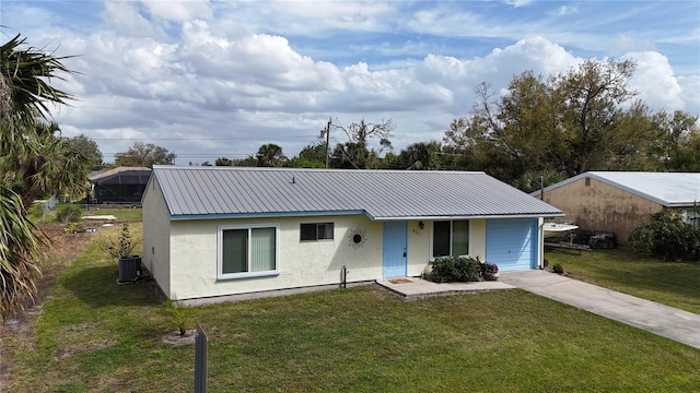 single story home featuring concrete driveway, metal roof, an attached garage, a front lawn, and stucco siding