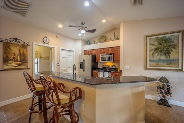 kitchen featuring appliances with stainless steel finishes, tile patterned flooring, visible vents, and a kitchen breakfast bar