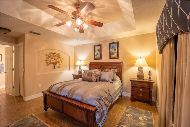 bedroom with tile patterned flooring, a raised ceiling, visible vents, and baseboards