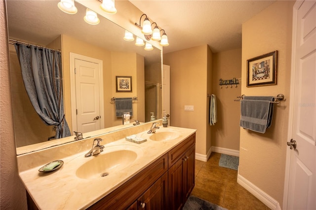 bathroom with double vanity, tile patterned flooring, baseboards, and a sink