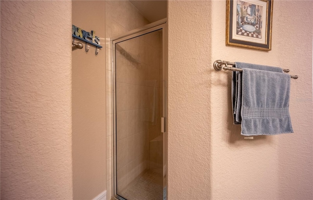 full bathroom with a textured wall and a shower stall