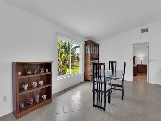 dining space featuring lofted ceiling, visible vents, and light tile patterned flooring