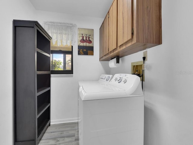 laundry room featuring baseboards, light wood-type flooring, cabinet space, and washer and dryer