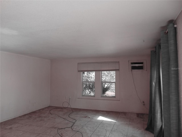 unfurnished room featuring an AC wall unit