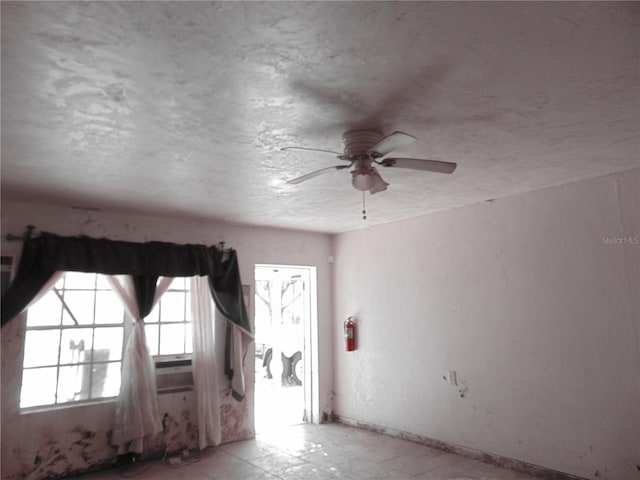 empty room featuring a ceiling fan, a textured ceiling, and baseboards