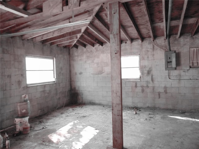 below grade area featuring a healthy amount of sunlight, electric panel, and concrete block wall