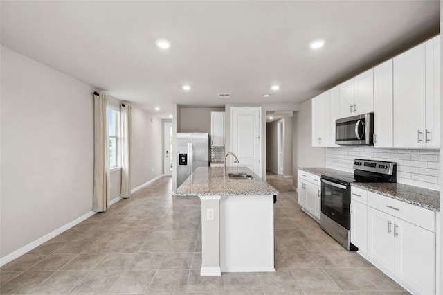 kitchen with a kitchen island with sink, a sink, visible vents, appliances with stainless steel finishes, and tasteful backsplash