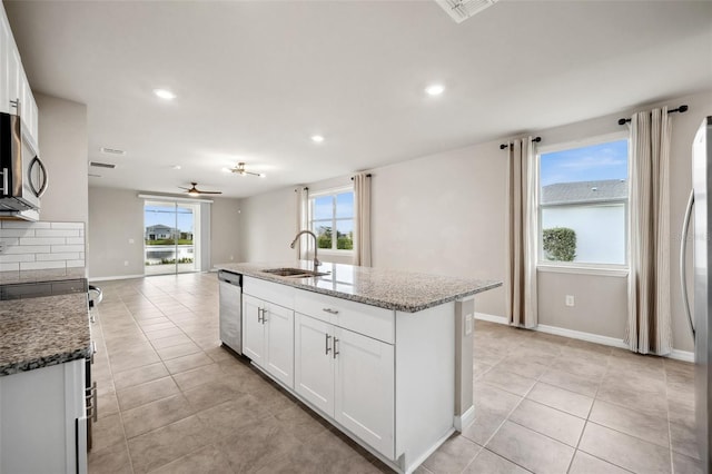 kitchen featuring light tile patterned floors, appliances with stainless steel finishes, stone countertops, and a sink