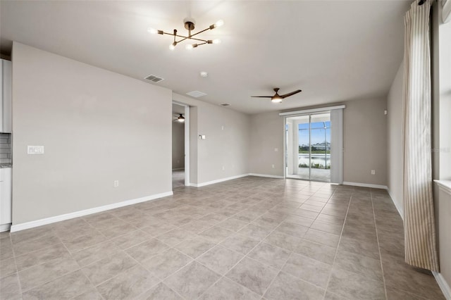 spare room featuring light tile patterned floors, visible vents, baseboards, and ceiling fan with notable chandelier