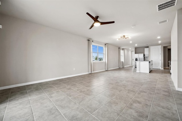 unfurnished living room with light tile patterned floors, baseboards, visible vents, and a ceiling fan