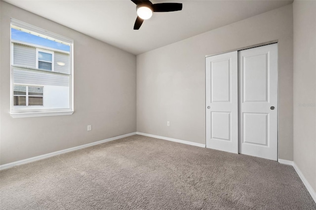 unfurnished bedroom with carpet floors, ceiling fan, baseboards, and a closet