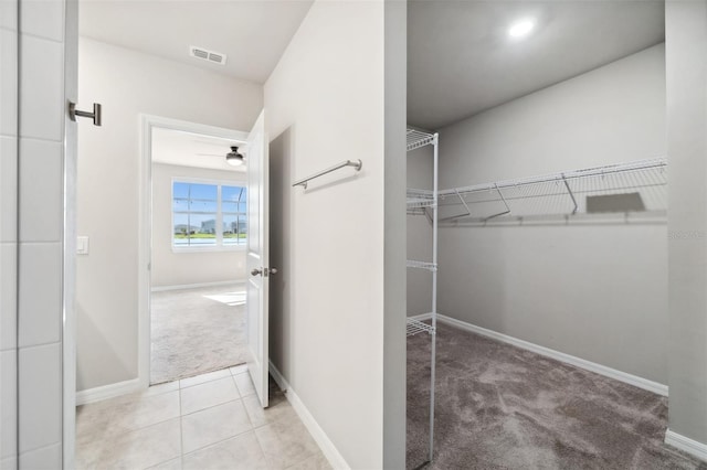 spacious closet featuring visible vents, light carpet, and light tile patterned floors