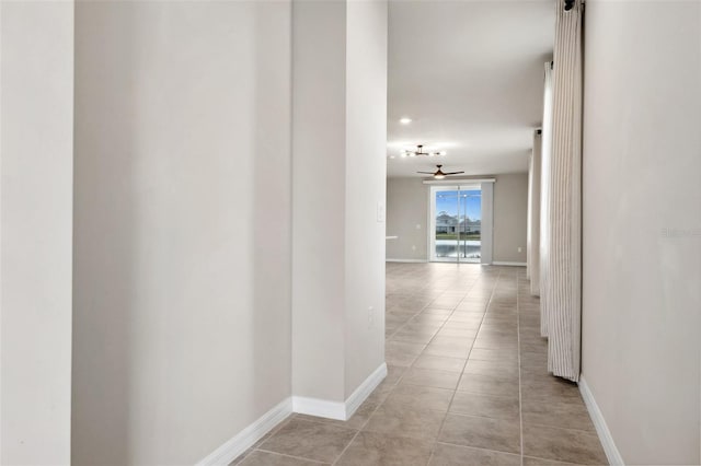 hallway with light tile patterned floors and baseboards