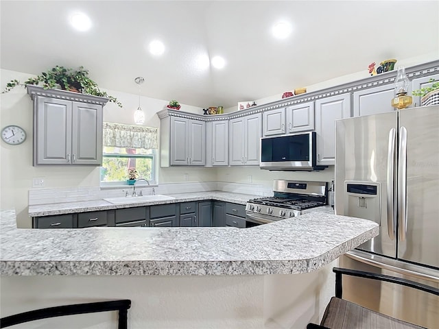 kitchen with a kitchen bar, gray cabinets, stainless steel appliances, and light countertops