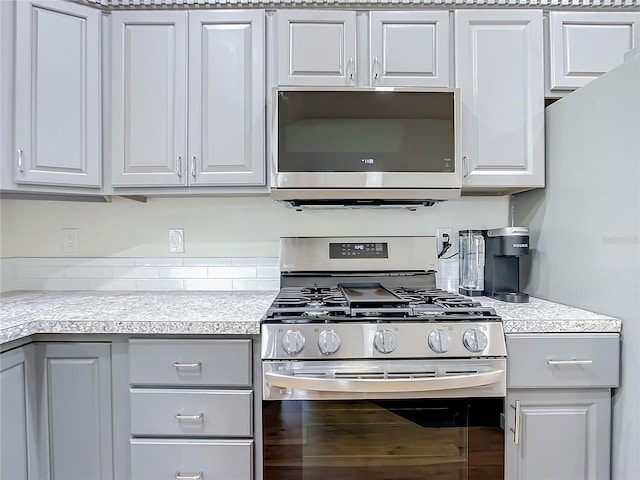 kitchen featuring stainless steel appliances, light countertops, white cabinetry, and gray cabinetry