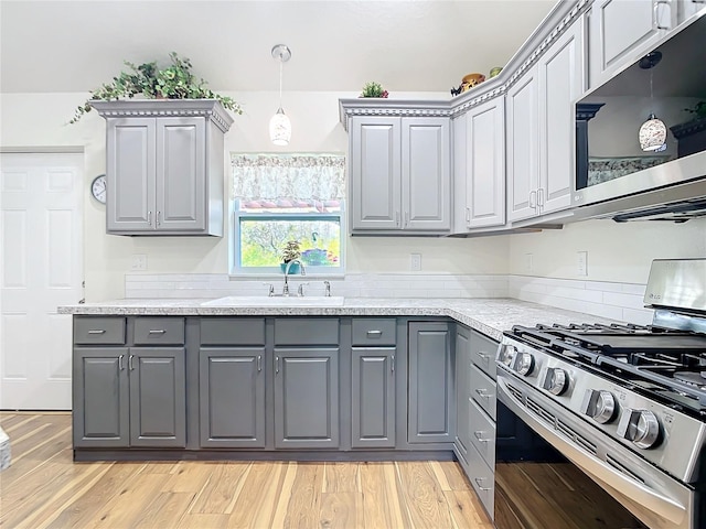 kitchen featuring stainless steel appliances, a sink, light wood-style flooring, and gray cabinetry