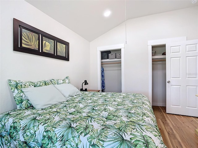 bedroom with lofted ceiling, two closets, and light wood-style flooring