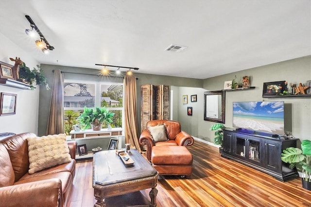 living room with track lighting, visible vents, and wood finished floors