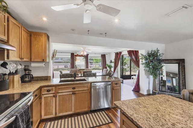 kitchen with light stone counters, stainless steel appliances, a peninsula, a sink, and open floor plan