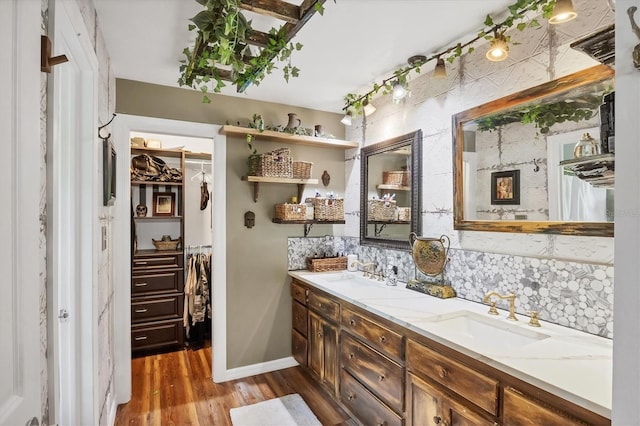 full bathroom featuring double vanity, wood finished floors, a sink, and decorative backsplash