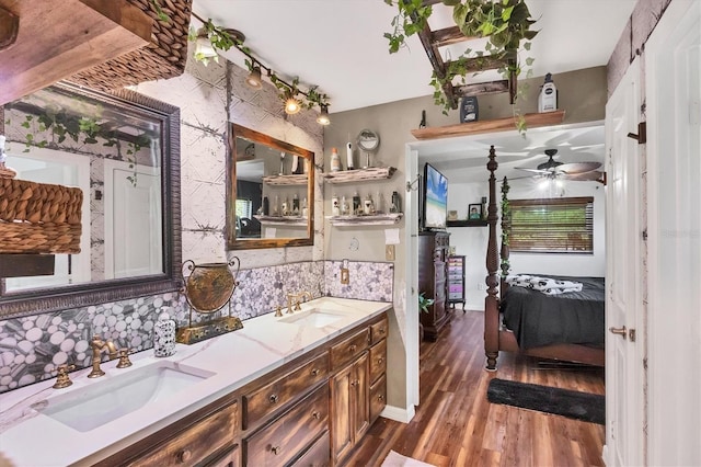 full bath with wood finished floors, tasteful backsplash, a sink, and ensuite bathroom