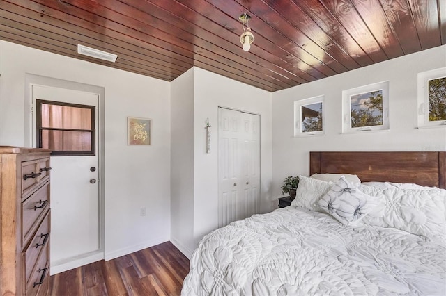 bedroom with dark wood-type flooring, wooden ceiling, a closet, and baseboards