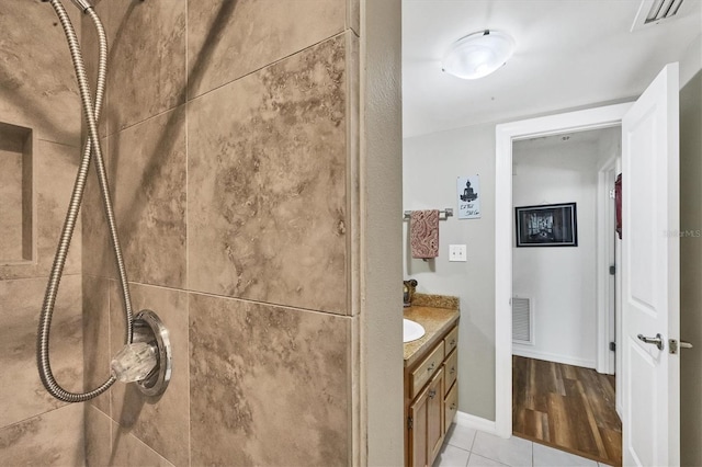 bathroom with tiled shower, vanity, visible vents, and tile patterned floors