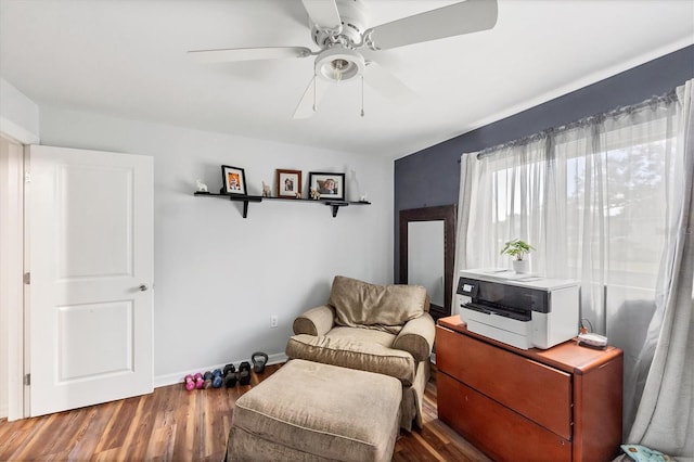 living area featuring ceiling fan, baseboards, and wood finished floors