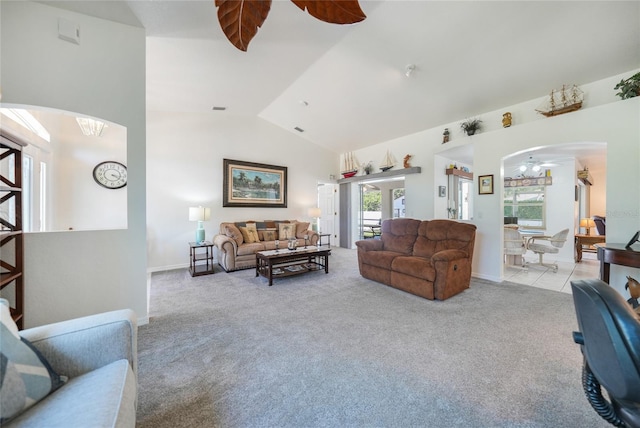 living area with vaulted ceiling, a ceiling fan, arched walkways, and light carpet