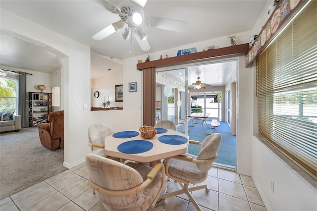 dining room featuring light carpet, baseboards, a ceiling fan, and light tile patterned flooring