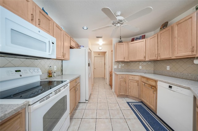 kitchen with light tile patterned floors, white appliances, light brown cabinets, and light countertops