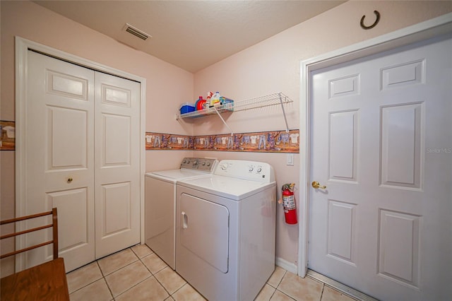 laundry area featuring visible vents, separate washer and dryer, light tile patterned flooring, and laundry area