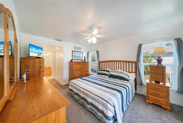 carpeted bedroom with arched walkways, visible vents, a ceiling fan, and baseboards