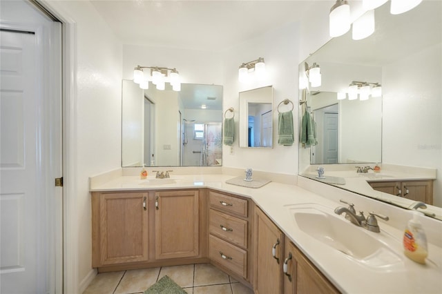 bathroom featuring tile patterned floors, double vanity, a shower stall, and a sink