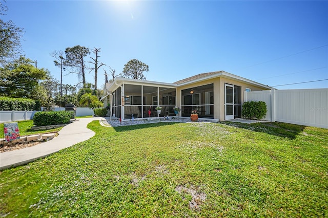 back of property with a lawn, a fenced backyard, and a sunroom