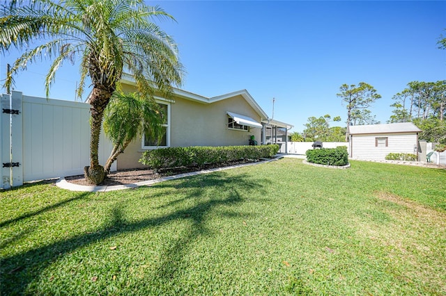 view of side of property with a gate, fence, a yard, stucco siding, and an outdoor structure