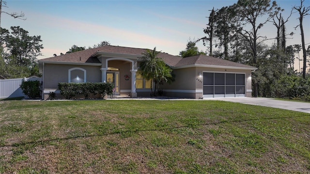 ranch-style house featuring concrete driveway, an attached garage, a front yard, and stucco siding