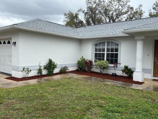 view of property exterior featuring a garage, a shingled roof, a lawn, and stucco siding