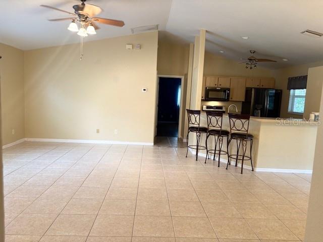 kitchen featuring ceiling fan, lofted ceiling, visible vents, black appliances, and a kitchen bar