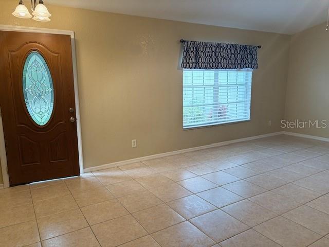 entrance foyer featuring light tile patterned floors, baseboards, and a chandelier