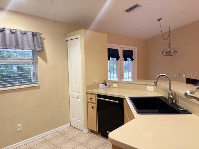 kitchen with light countertops, black dishwasher, visible vents, and a sink